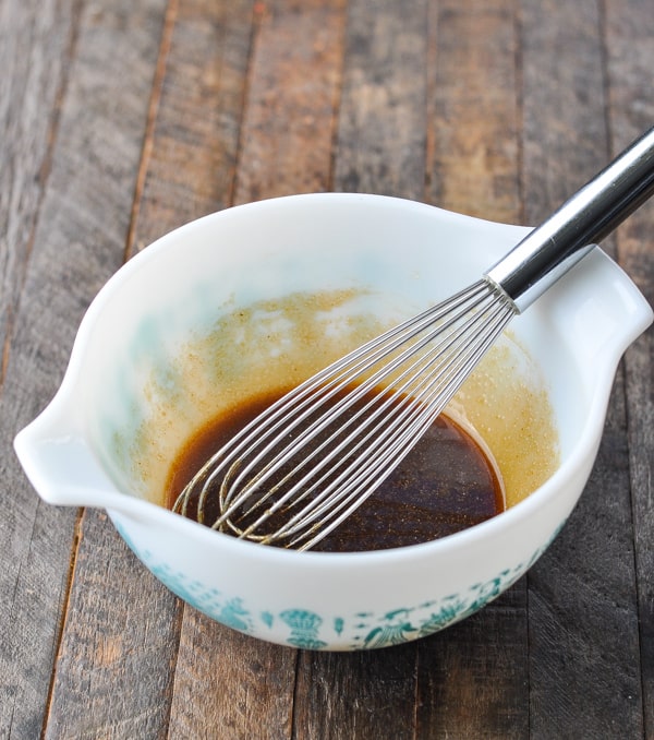 Brown sugar sauce for green beans in a white bowl with whisk