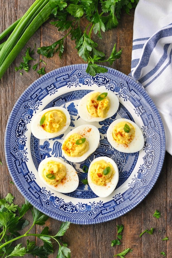 Overhead shot of deviled eggs on a blue and white plate on a wooden surface