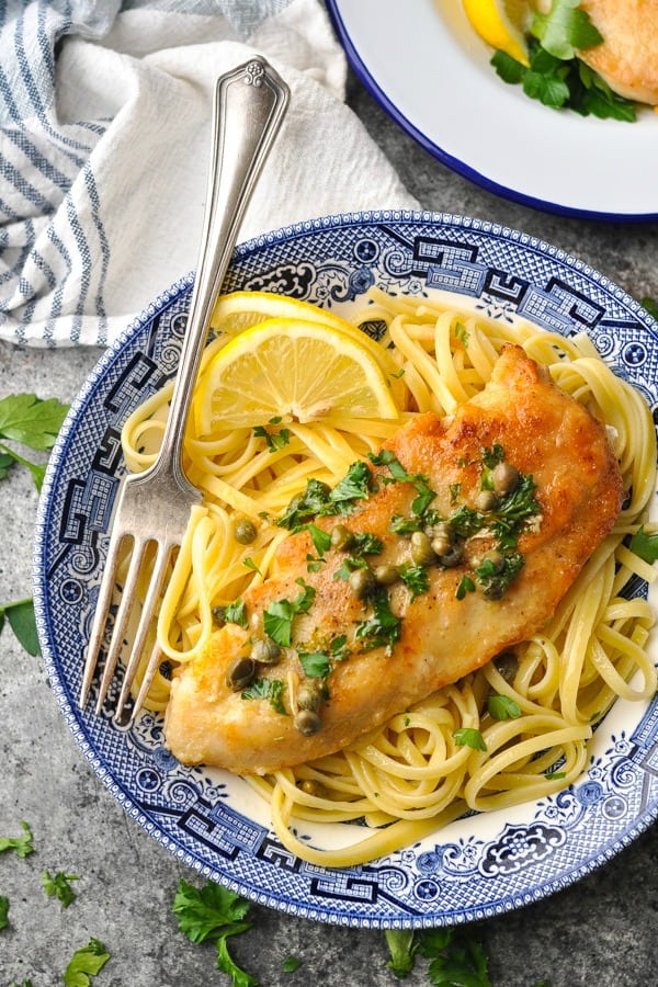 Close overhead shot of a bowl of lemon chicken piccata garnished with parsley