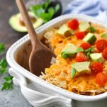 Wooden spoon in a nacho casserole with toppings