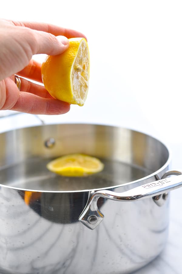 Squeezing lemon juice into pot of water