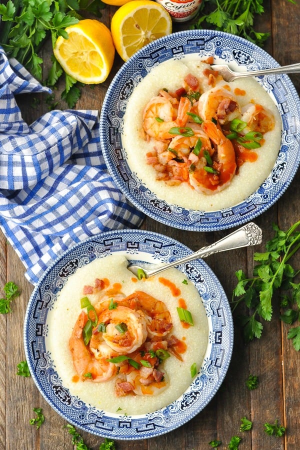 Overhead image of two bowls of shrimp and grits on a wooden table