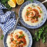 Overhead image of two bowls of shrimp and grits on a wooden table