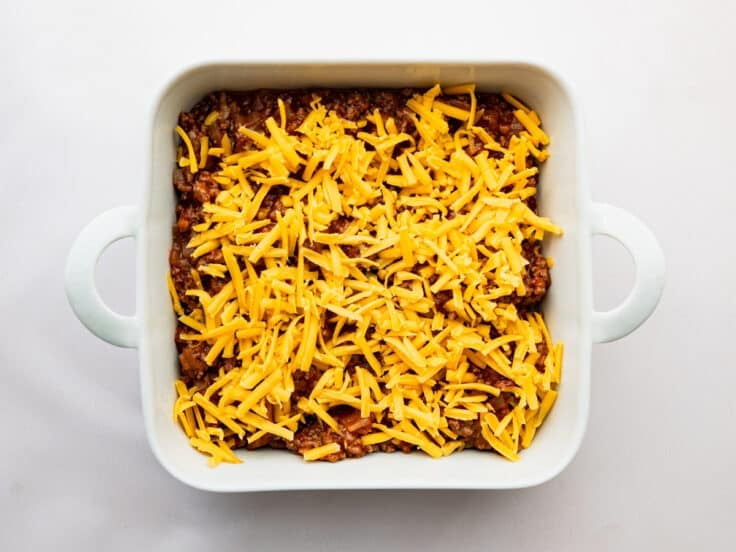 Adding cheese on top of the sloppy joe filling.