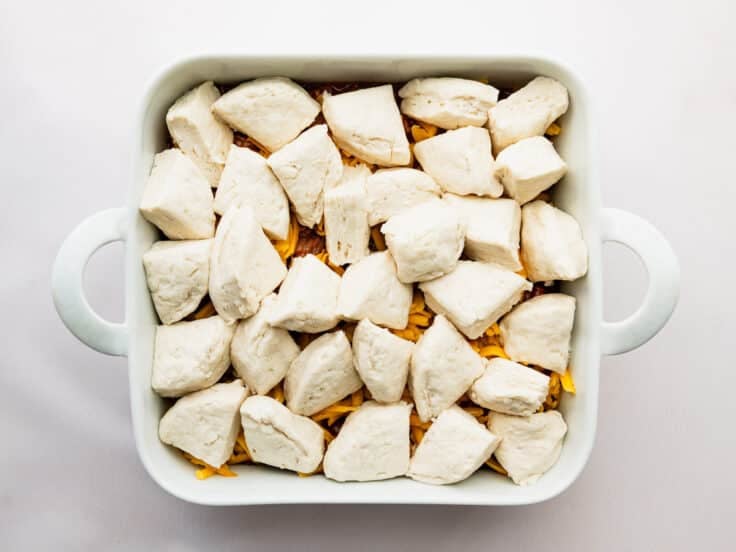 Adding the biscuits to the top of the casserole.