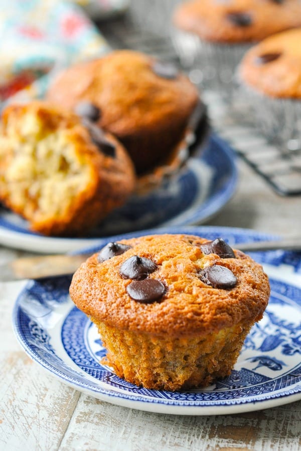 Close up front shot of banana chocolate chip muffin on a plate with more muffins in the background
