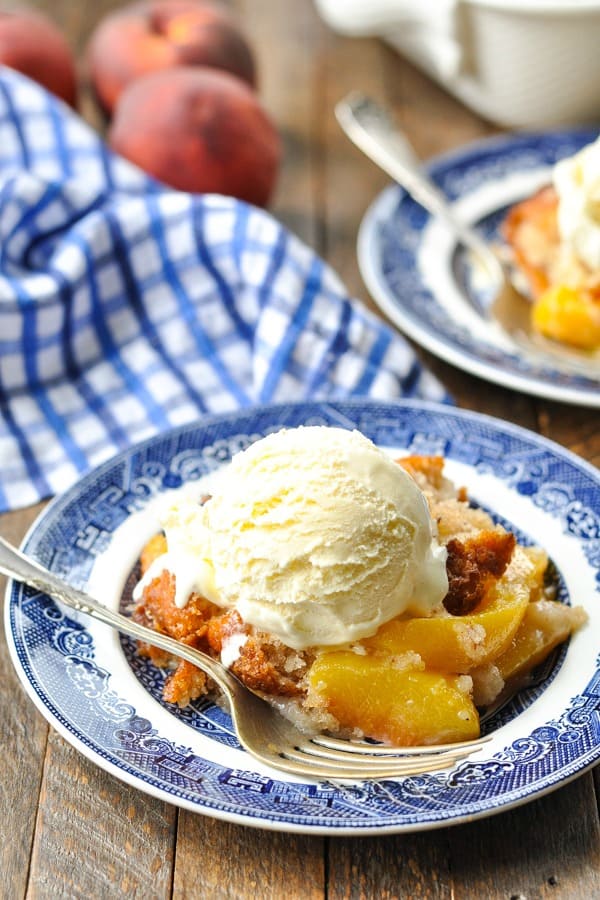 Close front shot of a plate of peach cobbler with bisquick and vanilla ice cream on top