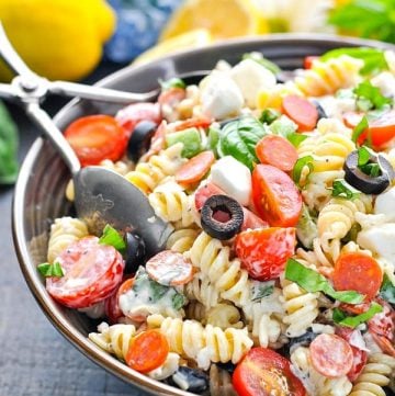 Front shot of a bowl of creamy pasta salad with serving tongs