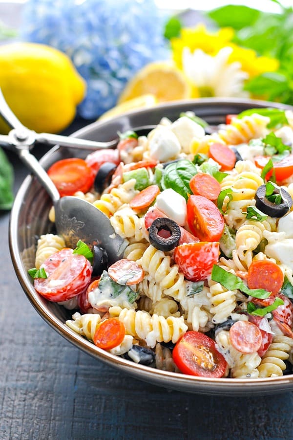 Front shot of a bowl of creamy pasta salad with serving tongs