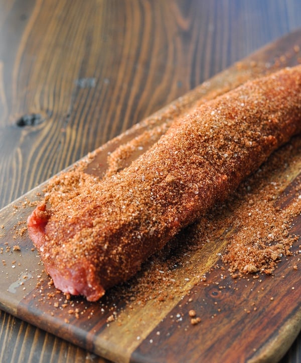 Pork tenderloin on a cutting board coated with spice rub