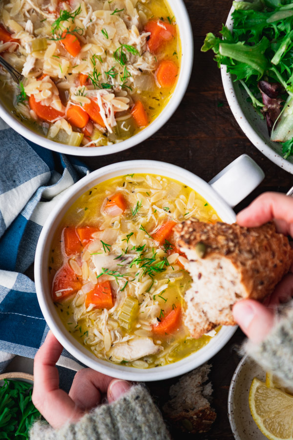 The best lemon chicken orzo soup recipe served with a side of bread for dipping.