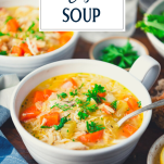 Side shot of lemon chicken orzo soup in a bowl with text title overlay