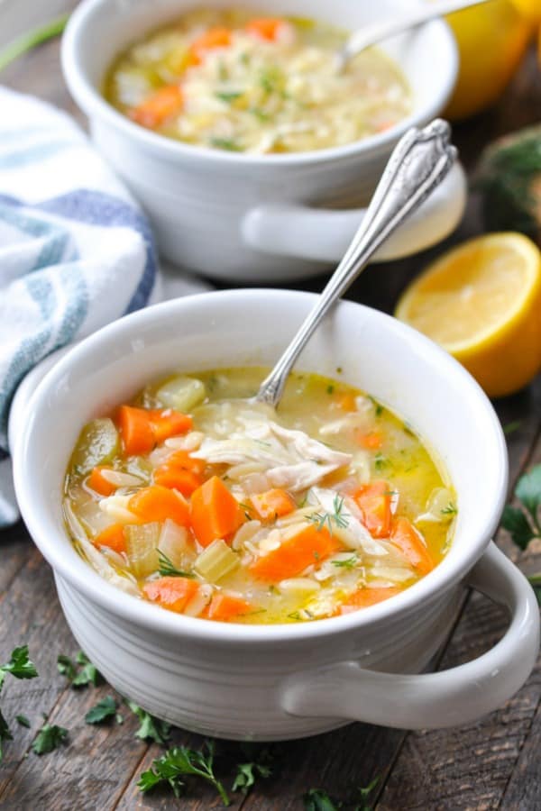 Front shot of lemon chicken soup with orzo in a white bowl on a wooden table