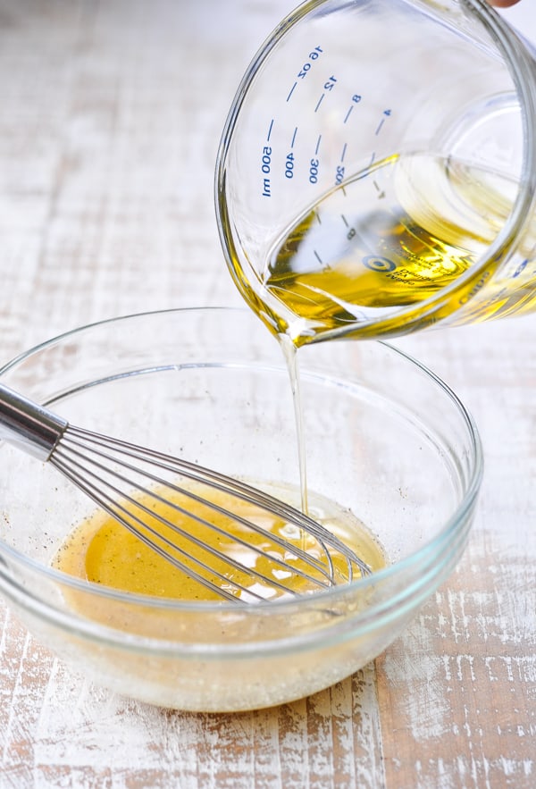 Pouring olive oil into vinaigrette dressing recipe