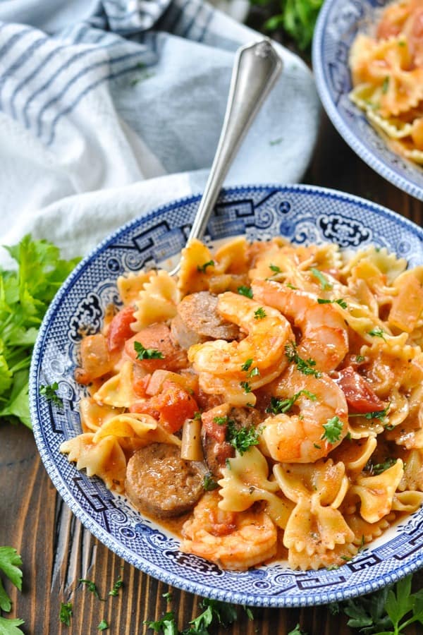 Close up front shot of shrimp and sausage pasta in a blue and white bowl
