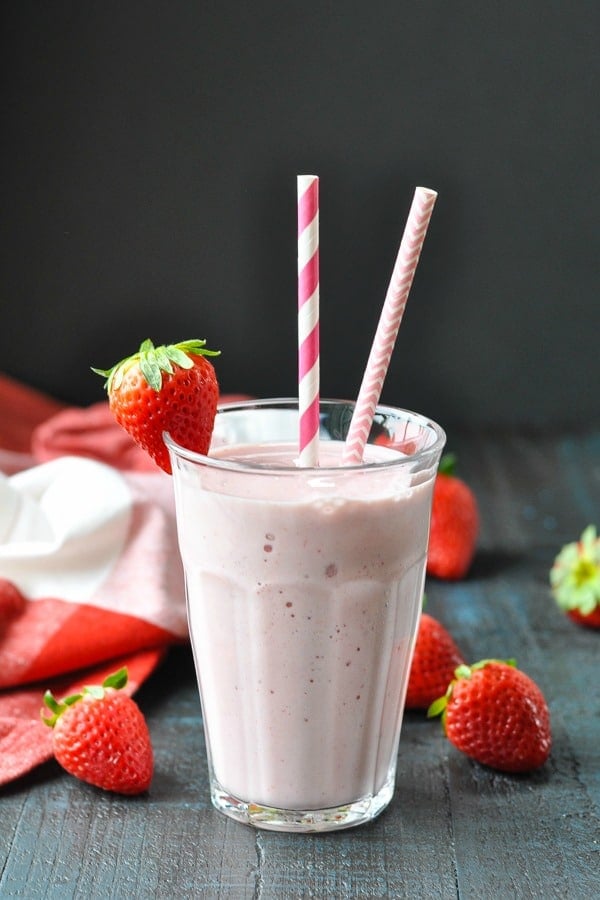 Healthy strawberry smoothie in a glass with a black background
