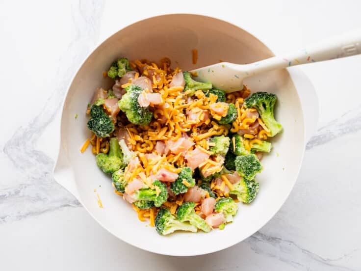 Stirring together the chicken broccoli cheese and pasta in a bowl.