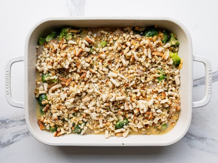 Adding the topping to a chicken broccoli pasta bake.