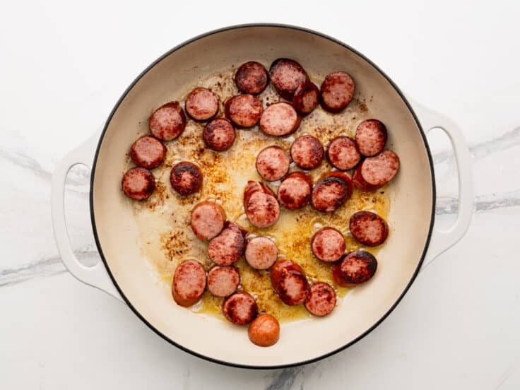 Browning the smoked sausage in a skillet.