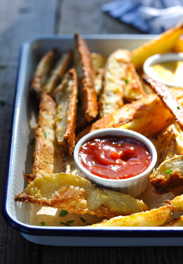 Tray of crispy baked potato wedges served with ketchup and honey mustard for dipping