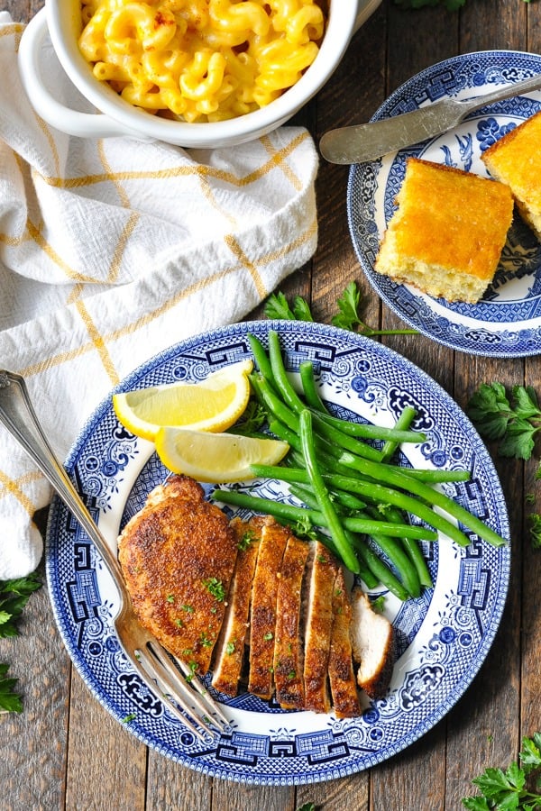 Overhead shot of blackened chicken breast on a blue and white plate with a side of green beans