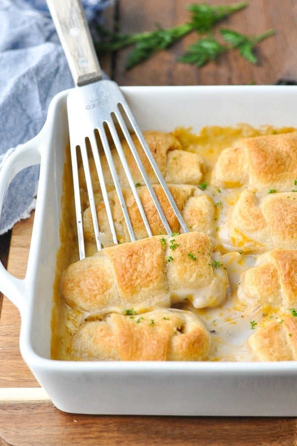 Front shot of cheesy canned chicken crescent rolls in a white baking dish garnished with parsley