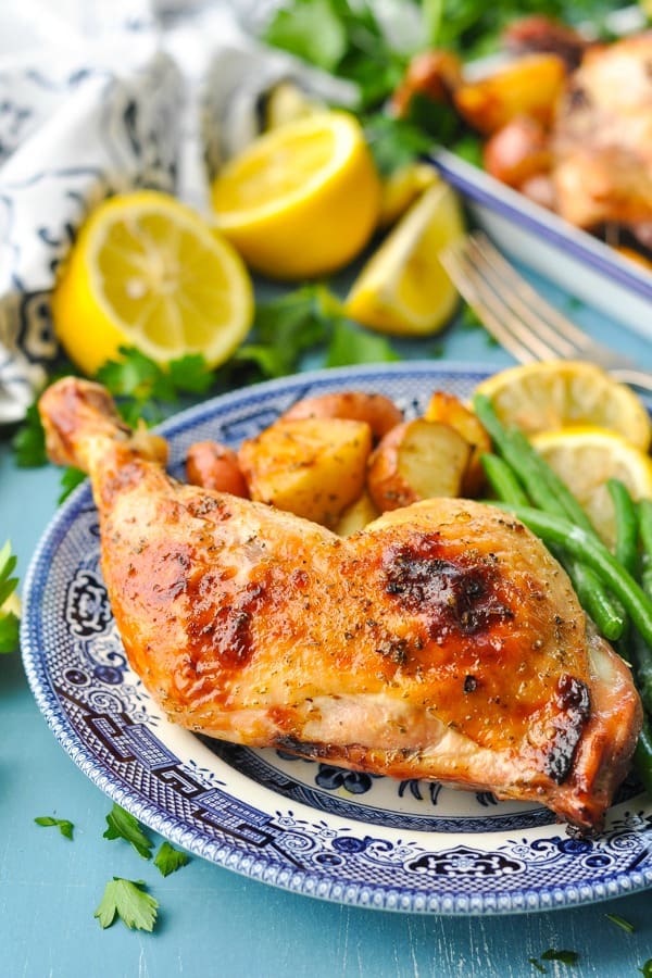 Front shot of Greek chicken and potatoes on a blue and white plate served with green beans