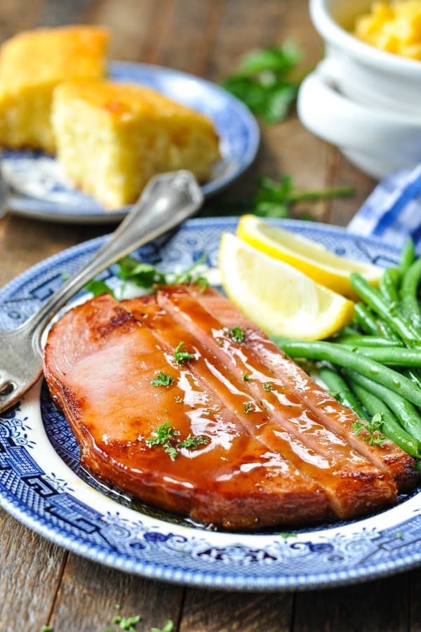 Front shot of glazed ham steak recipe served with green beans and cornbread