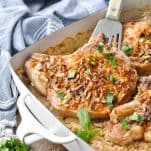 Front shot of baked pork chops with rice in a white casserole dish