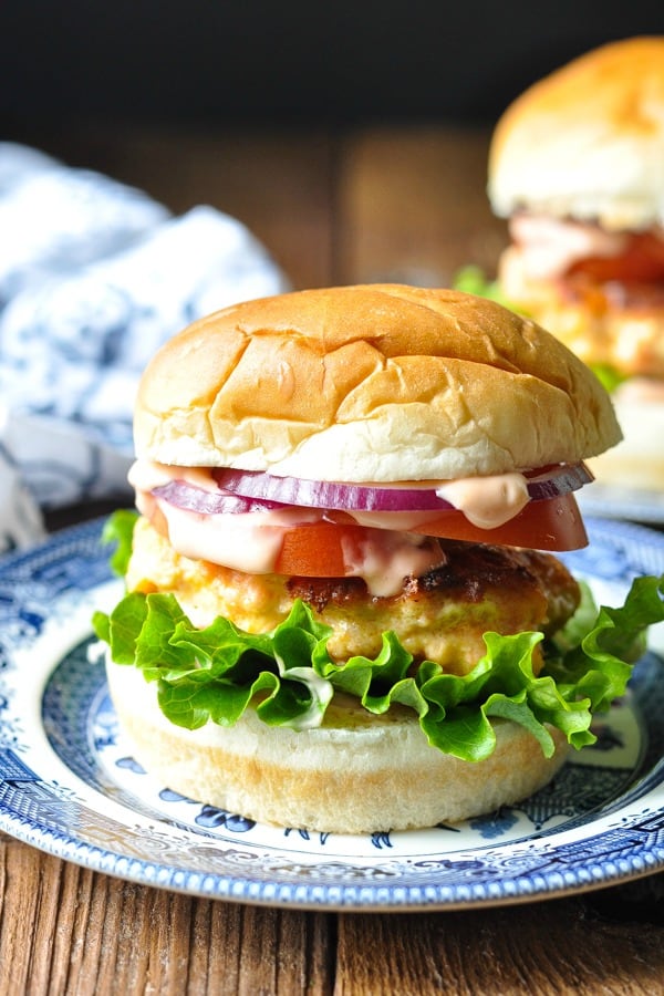 Front shot of a big homemade salmon burger recipe on a blue and white serving plate