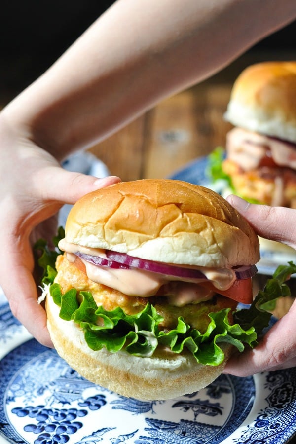 Vertical shot of hands holding a salmon burger on a bun