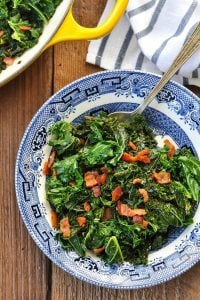 Close overhead shot of sauteed kale with bacon in a blue and white bowl