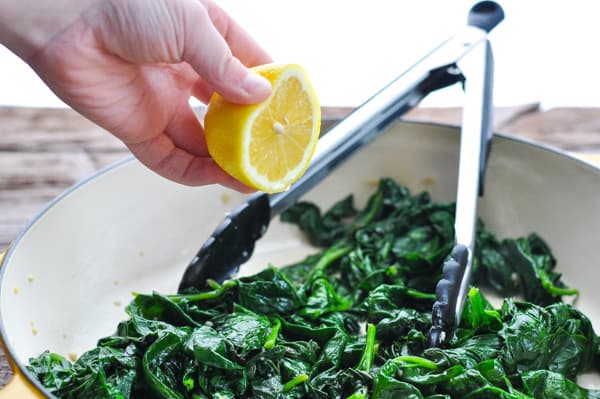 Squeezing fresh lemon juice over sauteed spinach