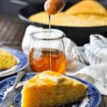 Front shot of drizzling honey on top of a slice of cornbread