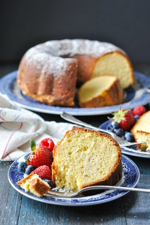 Slice of old fashioned sour cream pound cake on a plate with fresh berries