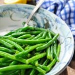 Side shot of a bowl of fresh green beans cooked with brown butter and lemon