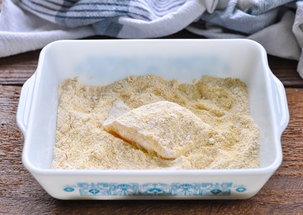 Dredging cod in cornmeal and flour breading mixture