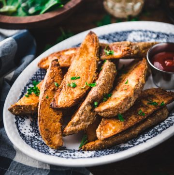Square featured image of a platter of crispy baked potato wedges with a side of ketchup
