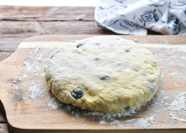 Round disc of scone dough on a wooden cutting board