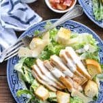 Plate of chicken caesar salad on a wooden table