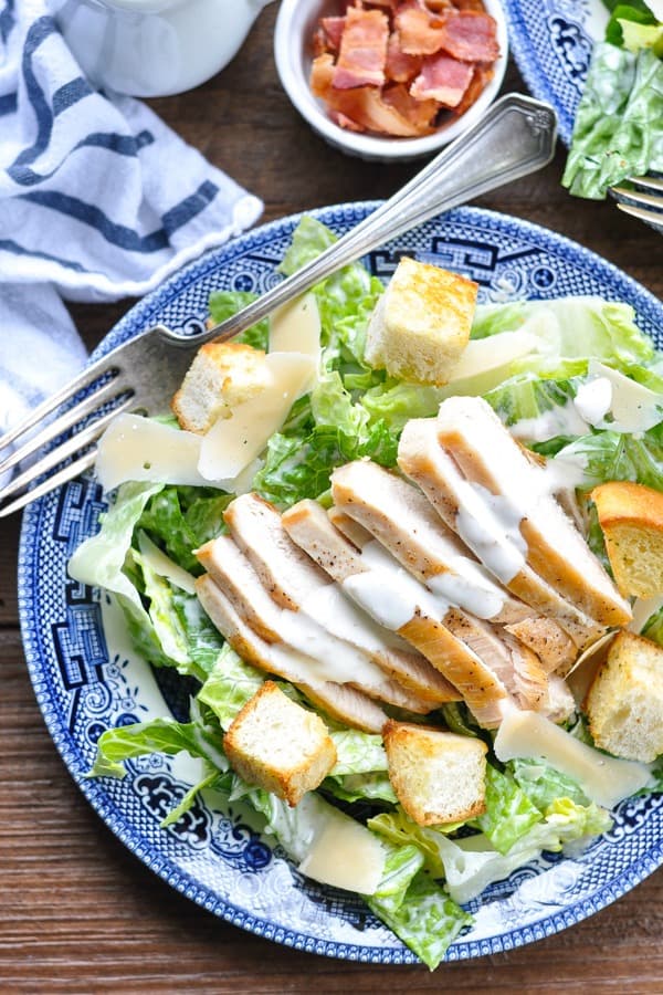 Close overhead shot of Chicken Caesar Salad on a plate with a blue and white striped towel nearby