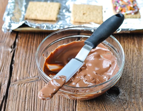 Melted chocolate chips in a glass bowl with an offset spatula for spreading
