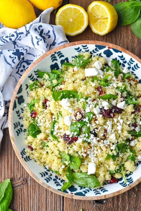 Close overhead shot of a bowl of couscous salad with cranberries surrounded by lemons