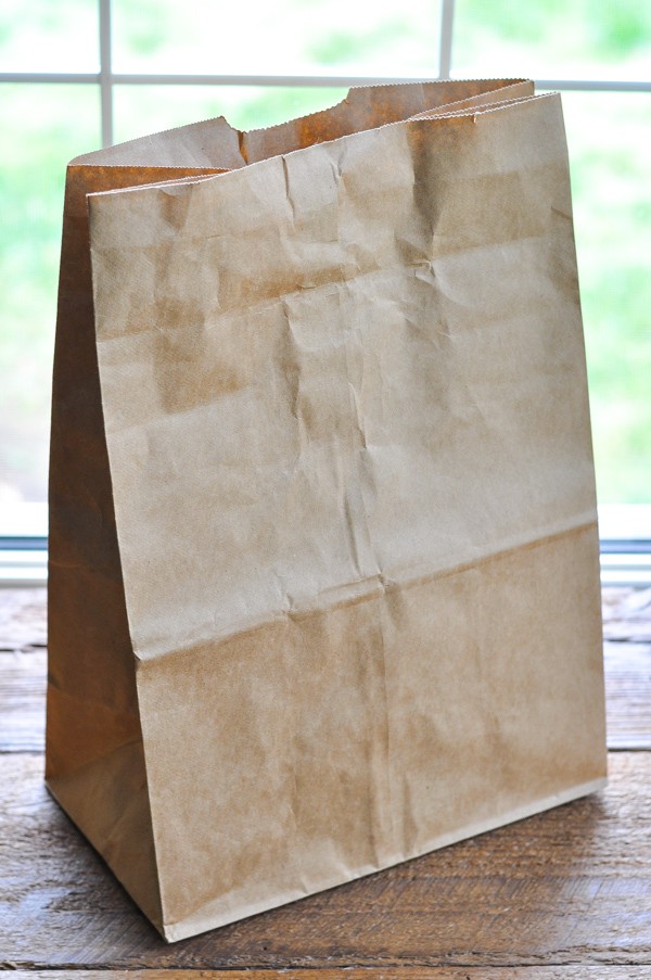 Brown paper bag on a wooden surface in front of a window
