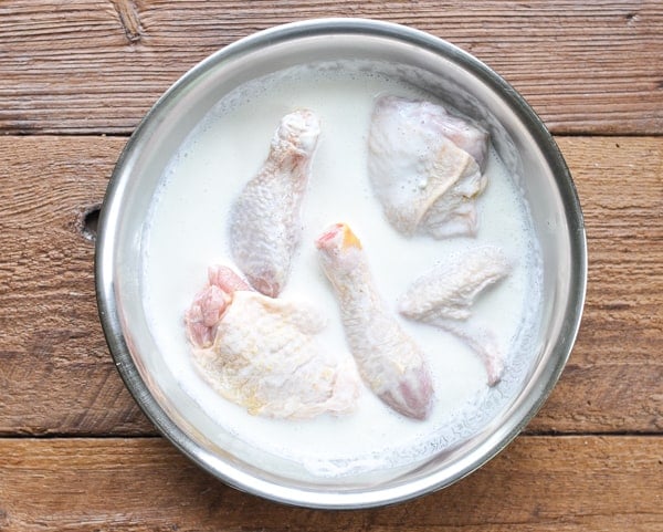 Soaking chicken pieces in a bowl of buttermilk
