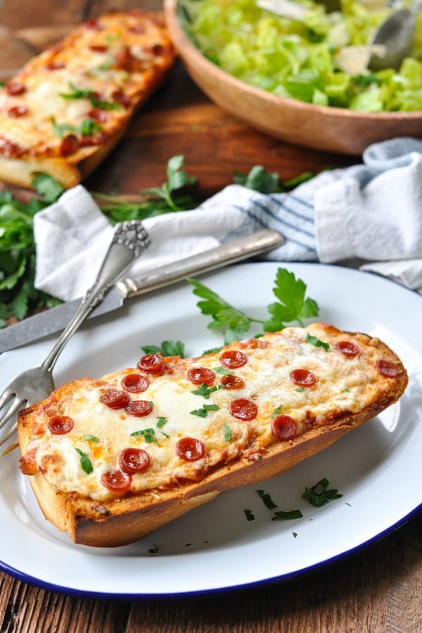 French bread pizza with a salad in the background