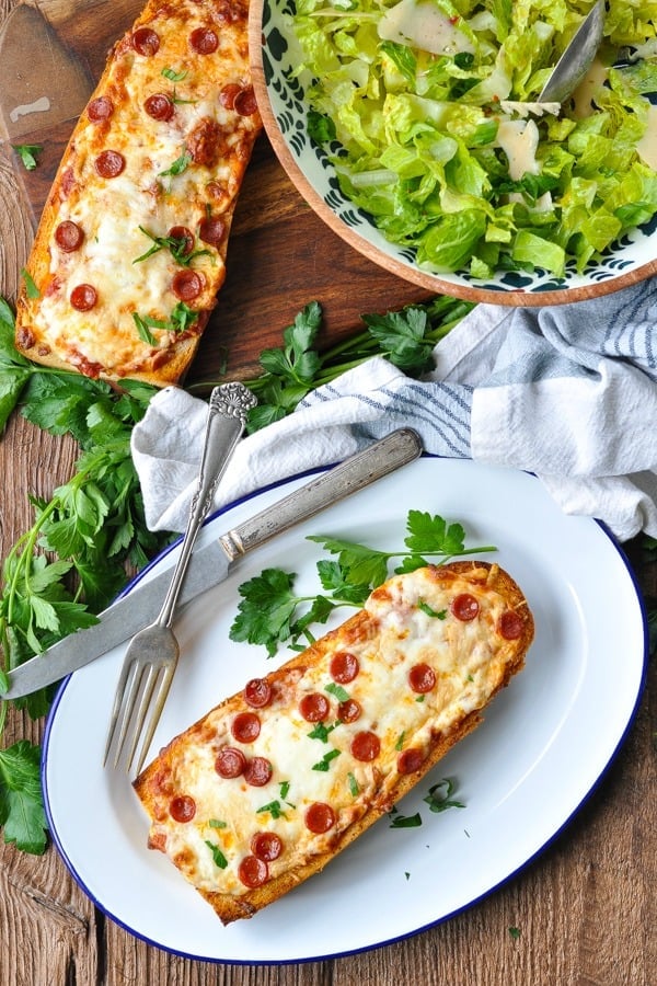 Overhead shot of two pieces of French Bread Pizza on a plate with a side salad