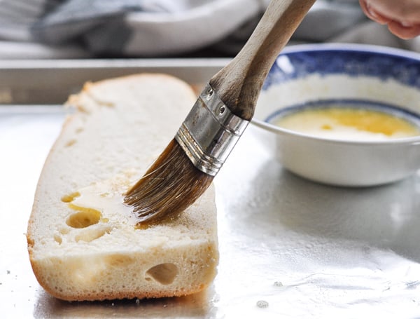 Brushing top of french bread with garlic butter