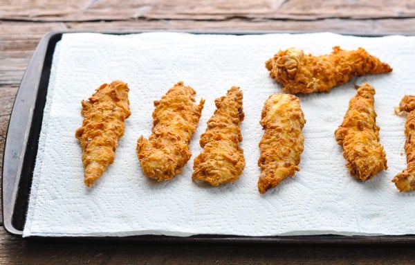 Draining fried chicken tenders on a paper towel