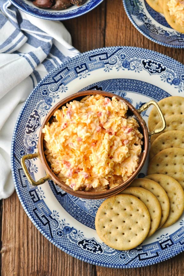 Close overhead shot of a plate of pimento cheese and crackers with a blue and white striped napkin nearby